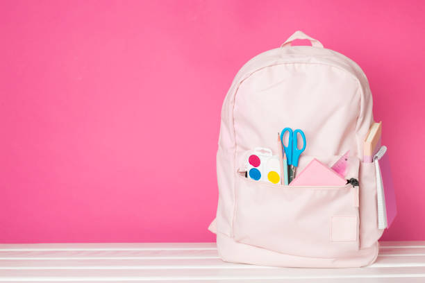 istock Pink school backpack with stationery on wooden table 1621391345
