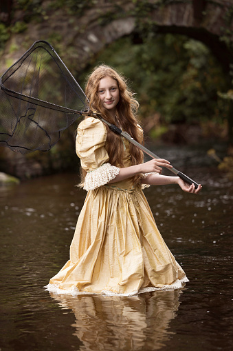 11-year-old girl standing in a stream ready to go fishing.