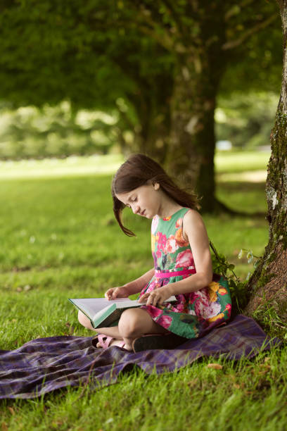 istock Six-year-old girl reading in the park 1621392525