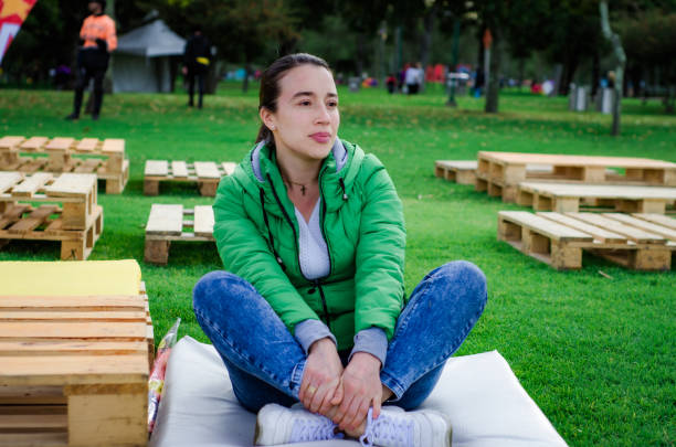 middle aged woman sitting alone in urban park stock photo