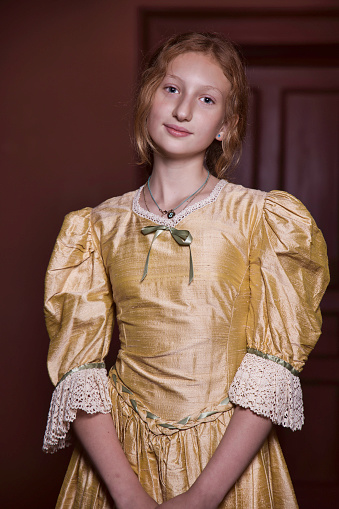 11-year-old blonde girl at home wearing a golden silk dress.