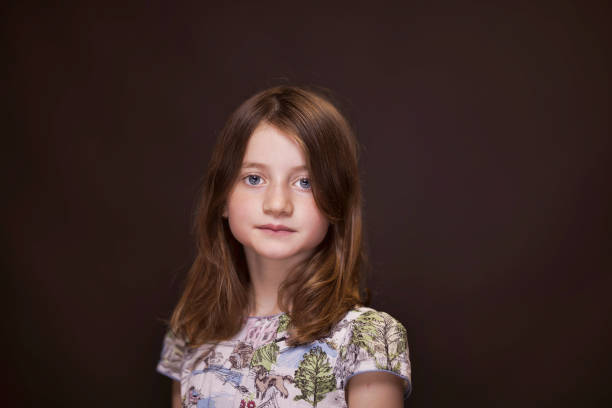 Portrait of a young caucasian girl, wearing a black turtleneck pullover and looking up to the left side. Black background.