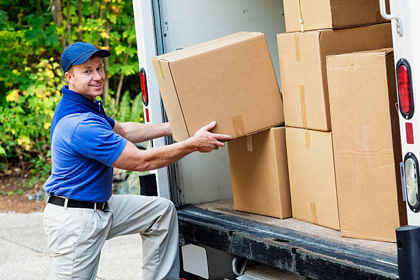 Delivery Man Photo of a delivery man lifting cardboard boxes from the back of his truck. company relocation stock pictures, royalty-free photos & images