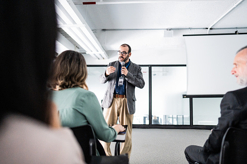 Businessman talking to employee/coworkers during a seminar at office