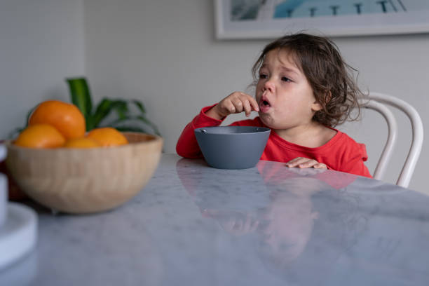 istock Sick toddler girl sits at dining table coughing 1621469800