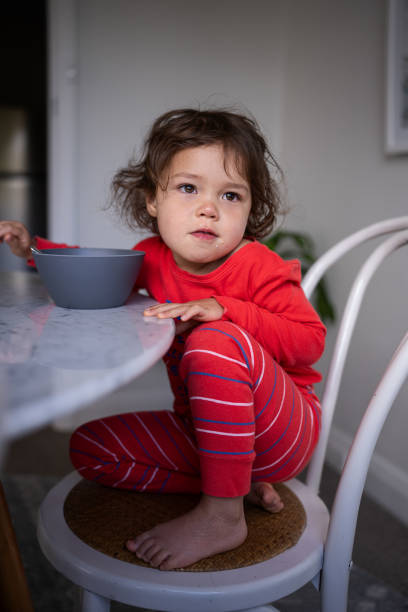 istock Sleepy little girl eating breakfast at dining table 1621469812
