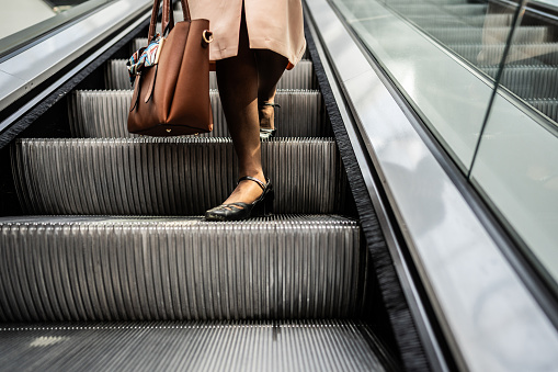 Low section of a businesswoman moving down on an escalator