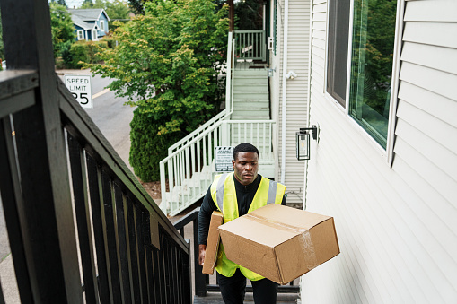 Delivery man walks up stairs, dropping off a package