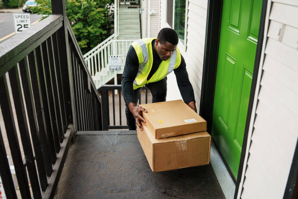 istock Delivery man drops a package off on a house's doorstep 1621478172