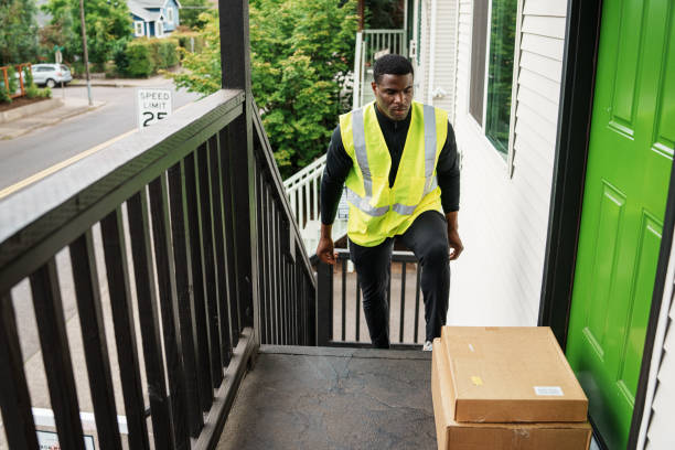 istock Delivery man drops a package off on a house's doorstep 1621478174