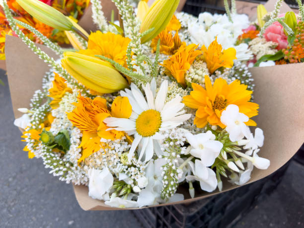 A view of a white and yellow floral bouquet, on display at a local farmers market.