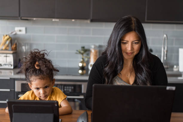 istock Mother works from home while daughter does online school next to her 1621498035