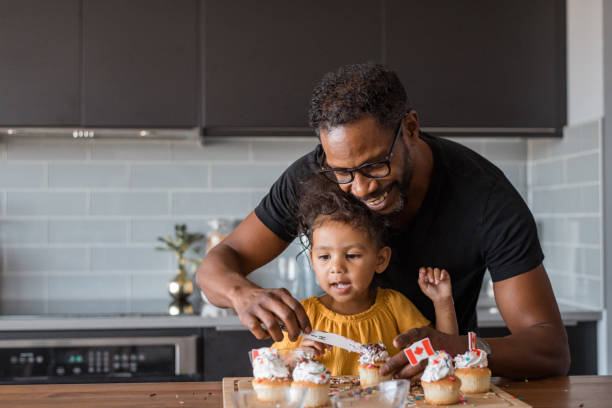 istock Father and young daughter decorate cupcakes at home 1621498047