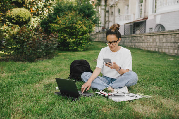 istock Young woman student studying using her books, laptop and notebook, sitting on grass. 1621520031