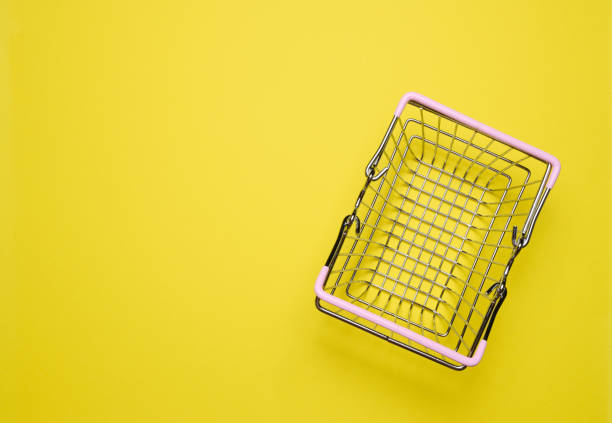 istock Empty miniature shopping cart on a yellow background, top view, representing the concept of shopping 1621520032