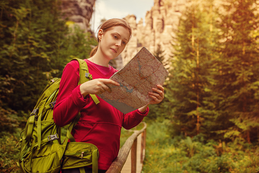 Young woman tourist with map portrait on forest background at autumn season. Focus on face.