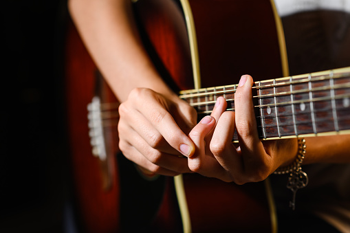The girl is learning to play the guitar. close-up. The student adjusts his fingers on the fretboard during training.