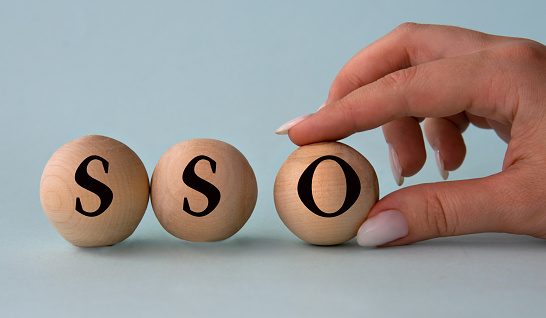 A woman's hand holds a wooden ball with the abbreviation SSO (Single sign-on). Business concept
