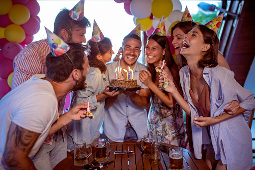 Group of friends celebrating birthday party together outdoors. Concept of celebrating and happiness.