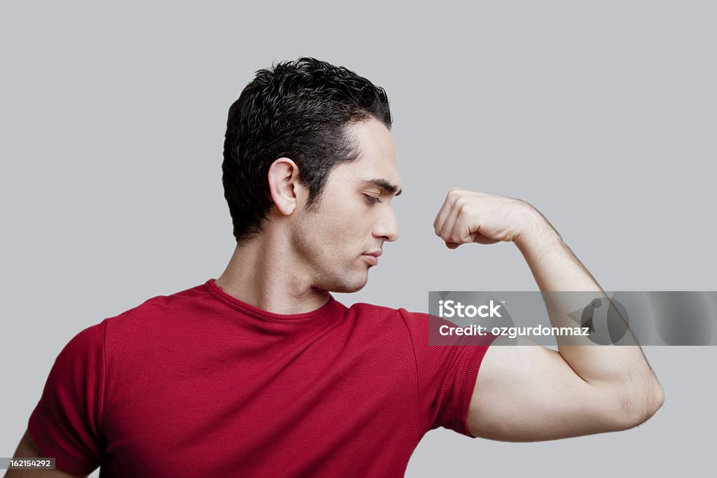 Młody człowiek Napinać mięśnie - Zbiór zdjęć royalty-free (Biceps)