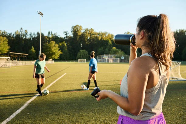 Young woman drinking water during a break from a teacm soccer practice