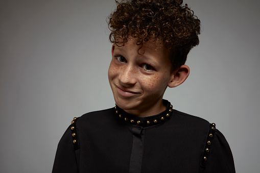 Portrait of a confident little boy with freckles and curly hair.