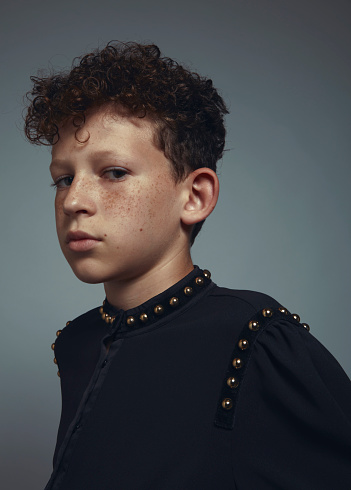 Portrait of a little boy with freckles, curly hair and jug ears.