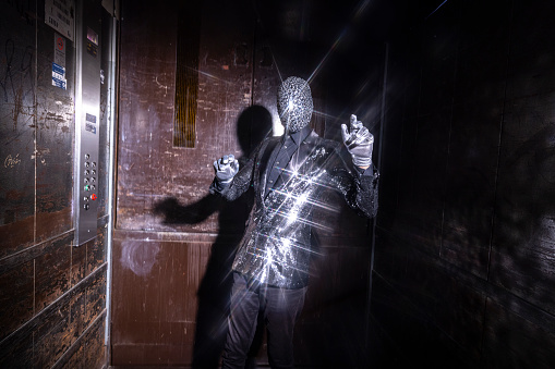 Mr discoball dancing in mirrored sparkling suit inside large industrial elevator