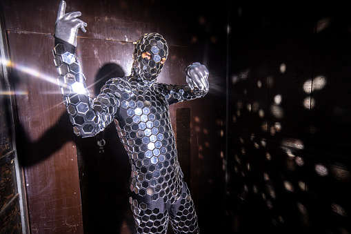 Mr discoball dancing in full mirrored  body suit inside large industrial elevator