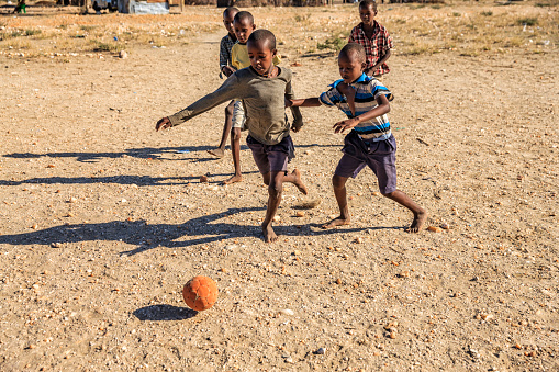 Barefoot African children  from Samburu tribe playing football in the village, East Africa, Kenya, East Africa. Samburu tribe is one of the biggest tribes of north-central Kenya, and they are related to the Maasai.