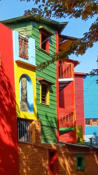 Buenos Aires, Argentina; Mar 4, 2023: Old traditional immigrant sheet metal and wood houses in the colorful Caminito street in La Boca neighborhood in Buenos Aires, Argentina. Sunny day.