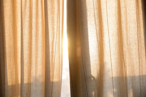 istock Sunlight breaking through curtains, summertime, golden hour time 1621738844