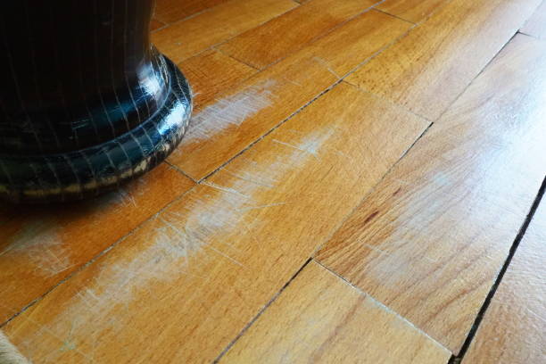 Scratched old parquet flooring needs maintenance. The parquet is damaged by scratches from prolonged use. The leg of an antique wooden bed scratched the floor stock photo