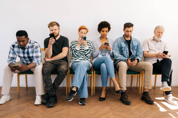 istock Front view of multicultural and different ages professional business people for vacancy in casual clothes sitting on chairs in row using mobile phones 1621767966