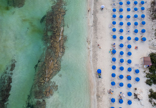 Drone aerial of tropical sandy beach holiday resort with beach umbrellas and people swimming and relaxing. Summer vacations. Landa beach Ayia Napa Cyprus