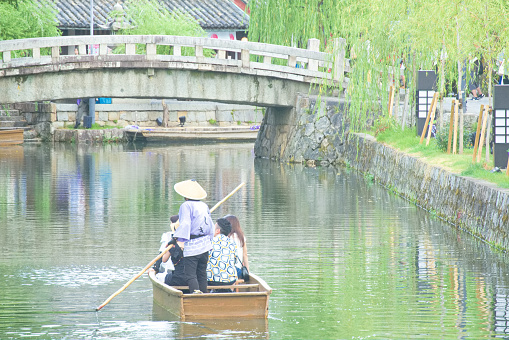 This is an image of tourists enjoying sightseeing river boats in the Kurashiki Bikan Historical Quarter. It can be used for any type of content, such as websites, blog posts, print, videos, etc.