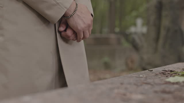 Unrecognizable Man Putting Hand on Cold Gravestone