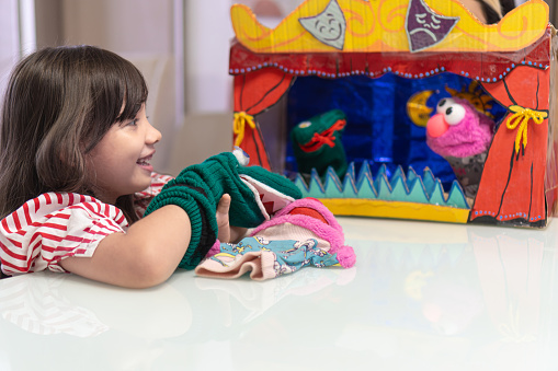 Little girl delighting in puppet play at home