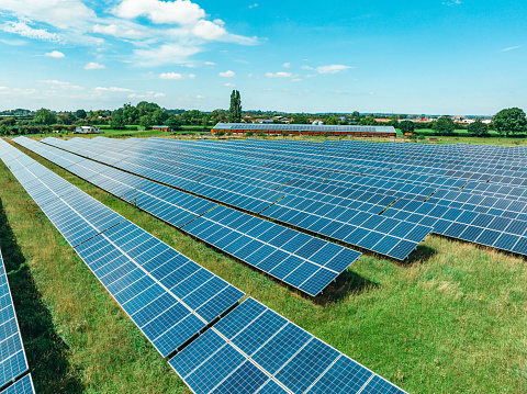 Aerial view of solar panels on green field at suburb in sunny day