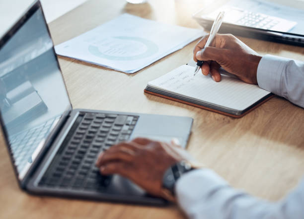 istock Man, laptop and hands writing notes for business schedule, office administration and reminder. Closeup worker, computer planning and notebook of ideas, information and strategy planner at table 1621885425