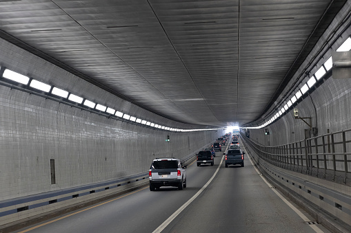 Cars navigate through an illuminated tunnel in Virginia: Hampton Roads Bridge Tunnels, Virginia - Norfolk route. Car point of view