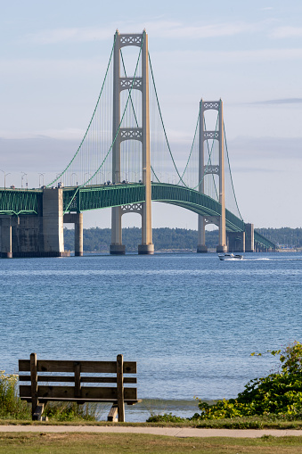 An empty bench with the Mackinaw Bridge in the distance