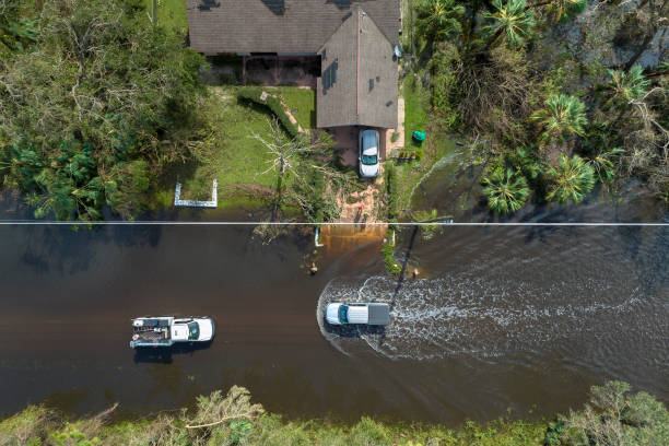 hurricane ian flooded street with moving cars and surrounded with water houses in florida residential area. consequences of natural disaster - assistência em catástrofes imagens e fotografias de stock