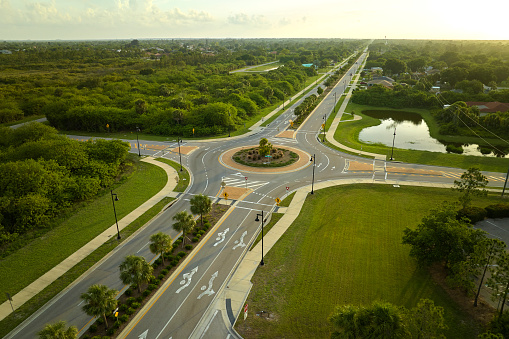 Aerial view of american suburban area with rural road roundabout intersection with moving cars traffic. Circular transportation crossroads in Florida.