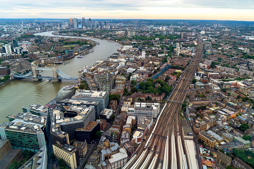 London, England, UK - July 26, 2023. London aerial panoramic view, a cityscape of the modern London skyline with boats on the River Thames, Tower Bridge and the extensive railway train network system, train  tracks.