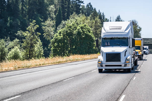 istock Convoy on big rig semi trucks with different semi trailers transporting cargo running on the straight multiline highway road at sunny day 1621984022