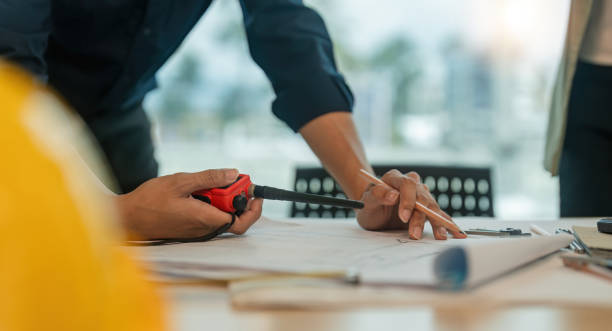 istock Closeup hand of engineer team with construction work plan discuss together blueprint on working table in construction site with safety helmet 1621995035