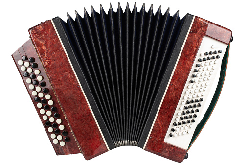 Old shabby musical instrument button accordion, on a table on a black background