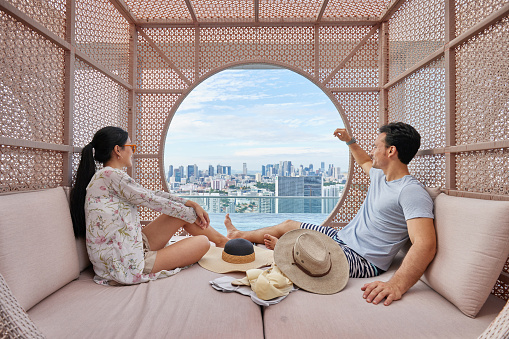 Asian couple relaxing in a cabana by the hotel pool