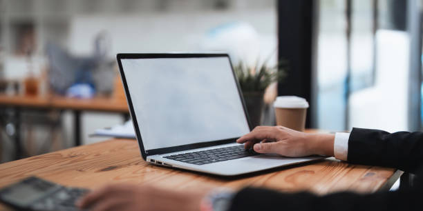 man hands typing on the laptop with empty blank white screen mockup. Computer is laying on the table. Person working from home concept. Copy space area for text